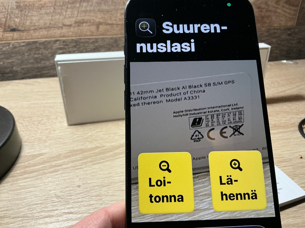 iPhonen Suurennuslasi-apps avattuna Avustettu Käyttö-tilassa. Näytöllä kookkaat "Loitonna" ja "Lähennä" painikkeet.