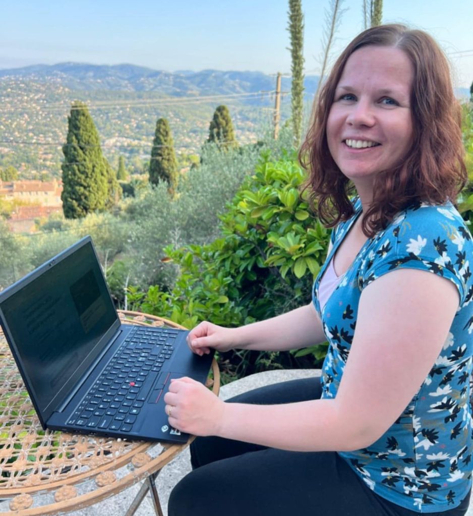 Valokuva Hanna Martikaisesta kannettavan tietokoneen äärellä aurinkoisessa kelissä.